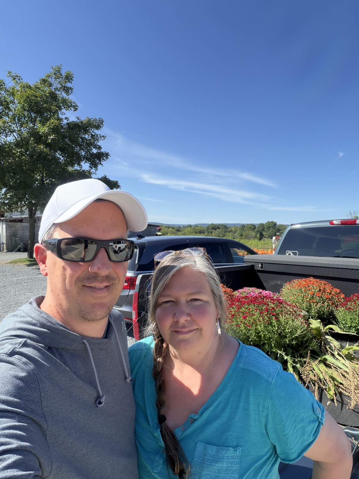 Two visitors beside a pickup truck carrying colorful mums.